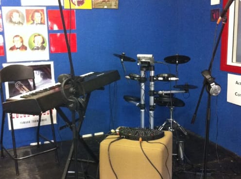 Small rehearsal space with instruments and soundproofing for group practice.